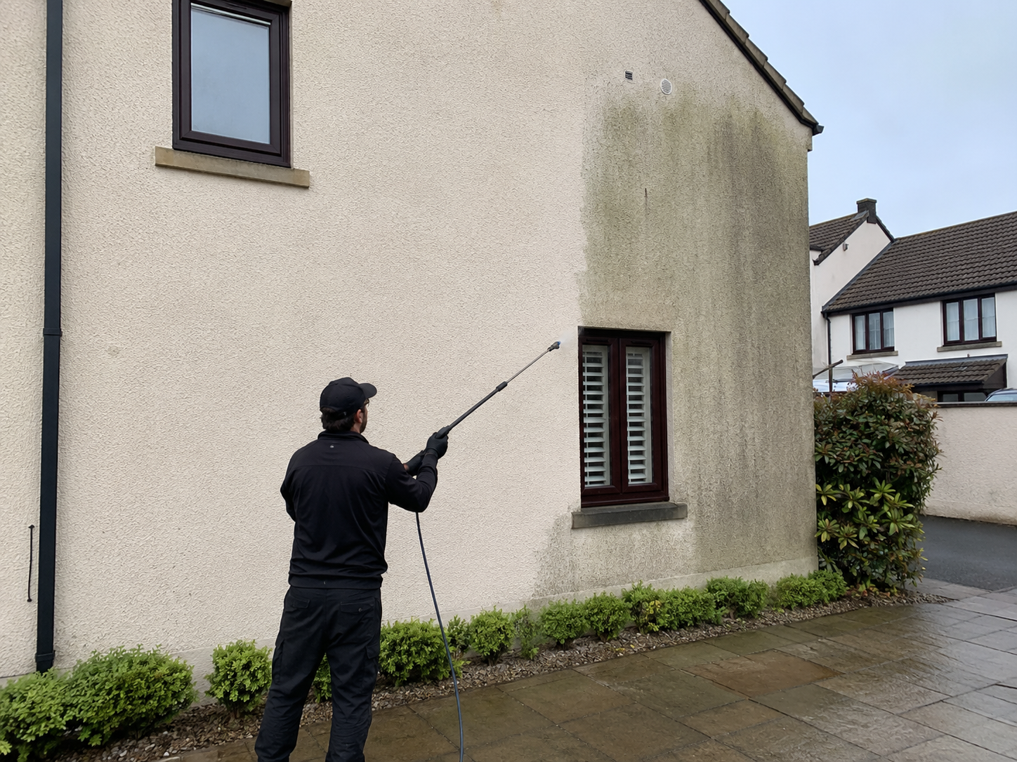 Norris Cleaning operative softwashing algae-stained render on a house in Bicester / Oxfordshire